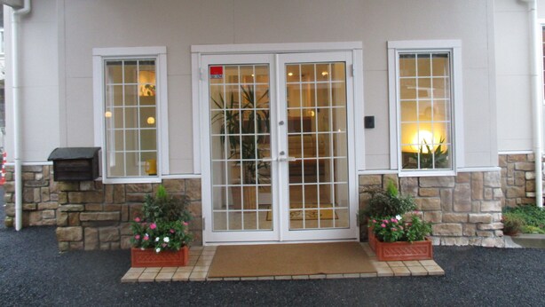 A building entrance with a stone facade, double doors with glass panels, and two flower planters. - Family Lodge Hatagoya Chiba Katsuura (Katsuura)