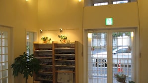 A reception area with a wooden bookshelf, a welcome mat, and a potted plant. - Family Lodge Hatagoya Chiba Katsuura (Katsuura)