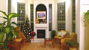 Uma sala de estar com lareira, árvore de Natal e diversas plantas.