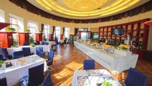 Eine großzügige Hotelhalle mit Bar im Zentrum, verschiedenen Sitzgelegenheiten und einem großen Kronleuchter.