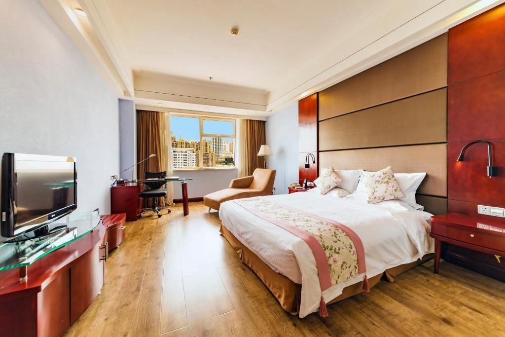 Habitación de hotel con una cama grande, televisión, escritorio con silla y ventana con vista a la ciudad.