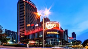 Ein modernes Hotel mit geschwungener Fassade, mehreren Etagen und beleuchteter Beschilderung.