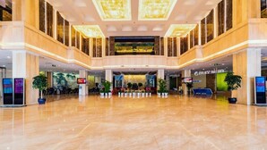Eine geräumige, moderne Lobby mit poliertem Marmorboden, hohen Decken und einem zentralen Atrium mit einer Sitzecke.