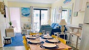 A dining area with a table set for six, yellow chairs, and a blue sofa in the background. - Beautiful beach Condo with ocean and pool view, very family oriented.  (Myrtle Beach)