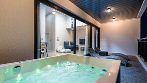 A spa area with a hot tub, seating, and a glass-enclosed room with a TV. - Modeul Spa Pension (Seogwipo)