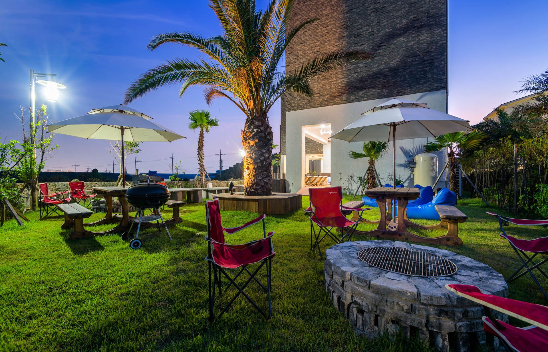 Un espace extérieur aménagé avec une terrasse, des sièges, un barbecue et des parasols.