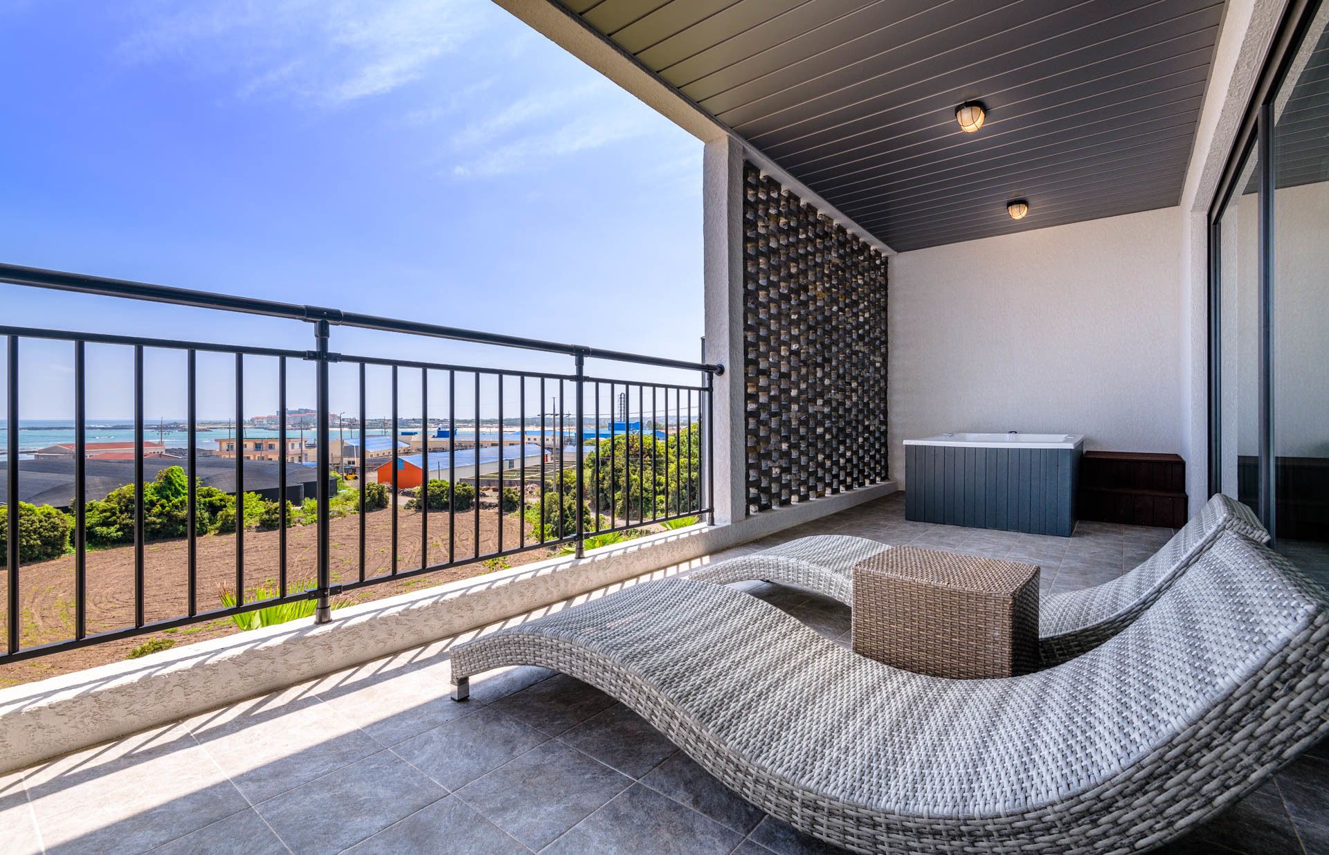 Een balkon met een rieten bank, een bijzettafeltje en een jacuzzi.