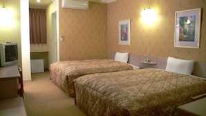 Ein Hotelzimmer mit zwei Betten, einem Fernseher und einem kleinen Schreibtisch.