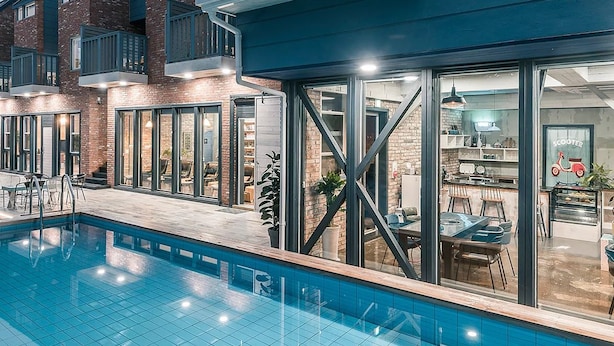 Um edifício residencial moderno com piscina, grandes portas de vidro e varanda.