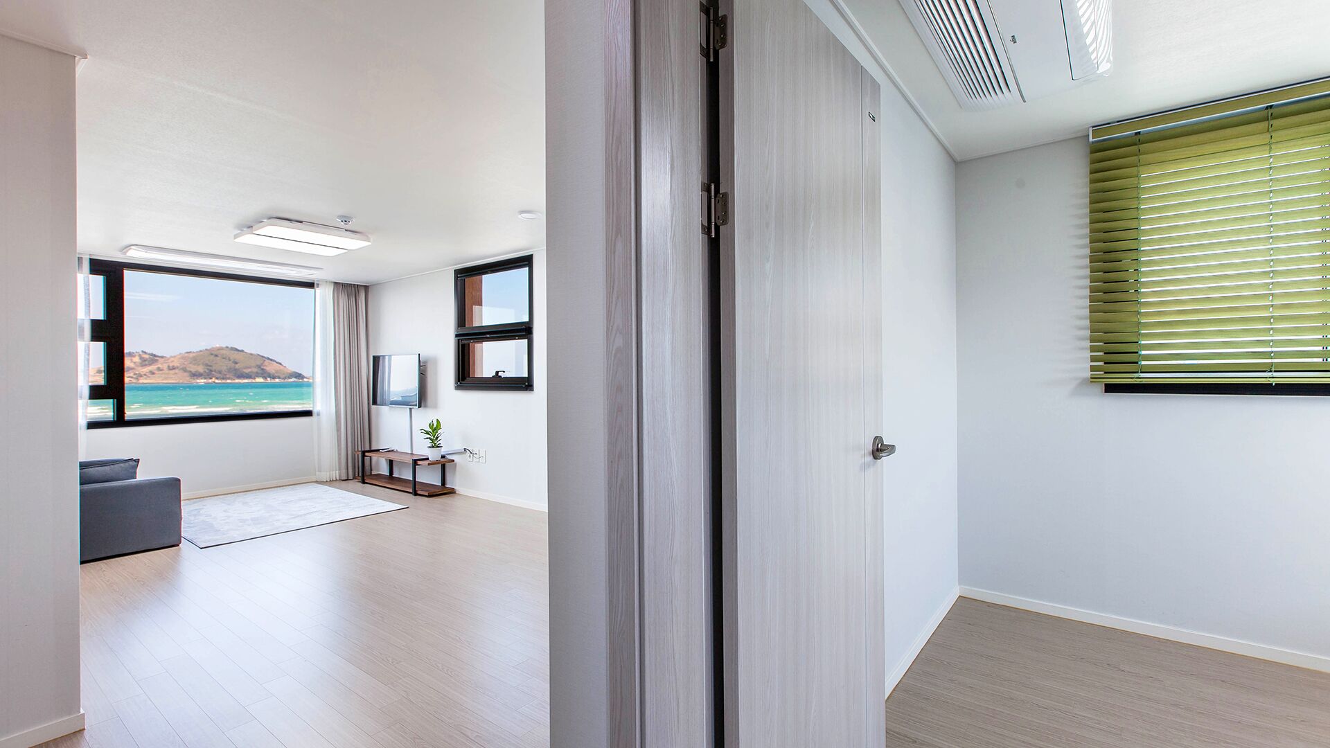 Una habitación moderna y luminosa con un ventanal grande que ofrece vistas panorámicas del mar y las colinas.