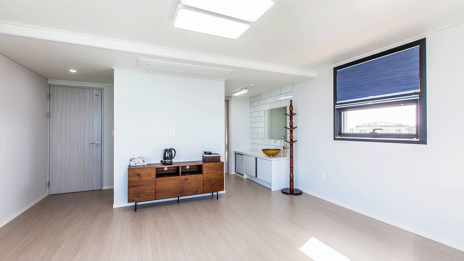 Una cocina moderna con un armario de madera, un lavamanos y una ventana con persianas.
