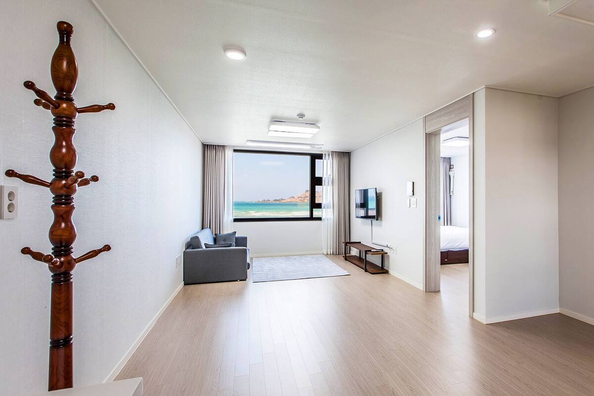 Ein modernes Hotelzimmer mit Holzboden, einer Couch, einem Fernseher und Meerblick.