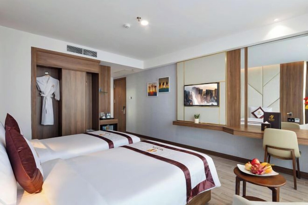 A hotel room with two beds, a seating area, a TV, and a large mirror.