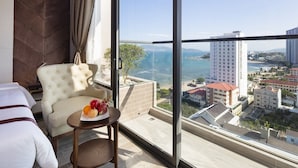 Quarto de hotel com uma grande janela com vista para a paisagem costeira.