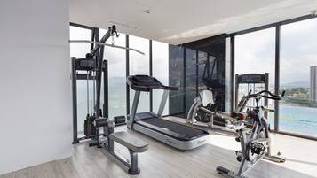 Et moderne fitnesscenter med løbebånd, crosstrainer og vægtmaskine, store vinduer med udsigt over byen.