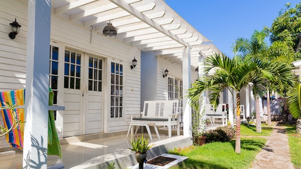 Une maison blanche avec un porche abrité, un petit jardin et un chemin.