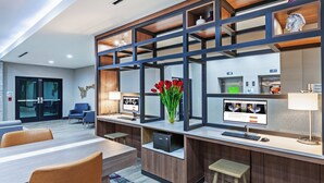 Un hall d’hôtel moderne avec un comptoir d’accueil, un espace salon et une grande fenêtre.