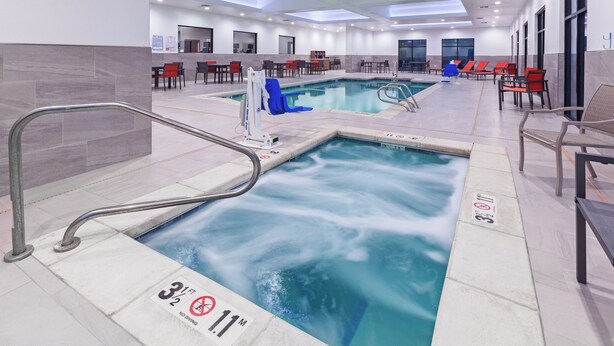 Un espace piscine d’hôtel comprenant un jacuzzi, des chaises longues et un coin salon.