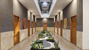 A hotel corridor with a central garden, wooden doors, and patterned wall decorations. - Sakura Terrace Setiabudi (Jakarta)
