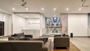 A modern lobby with a reception desk, seating area, and a view of the staircase leading to the upper floors. - Sakura Terrace Setiabudi (Jakarta)