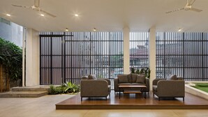A modern living room with a sectional sofa, a coffee table, and a view through large windows. - Sakura Terrace Setiabudi (Jakarta)