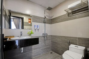 A modern bathroom with a black countertop sink, a mirror, a shower, and a toilet.