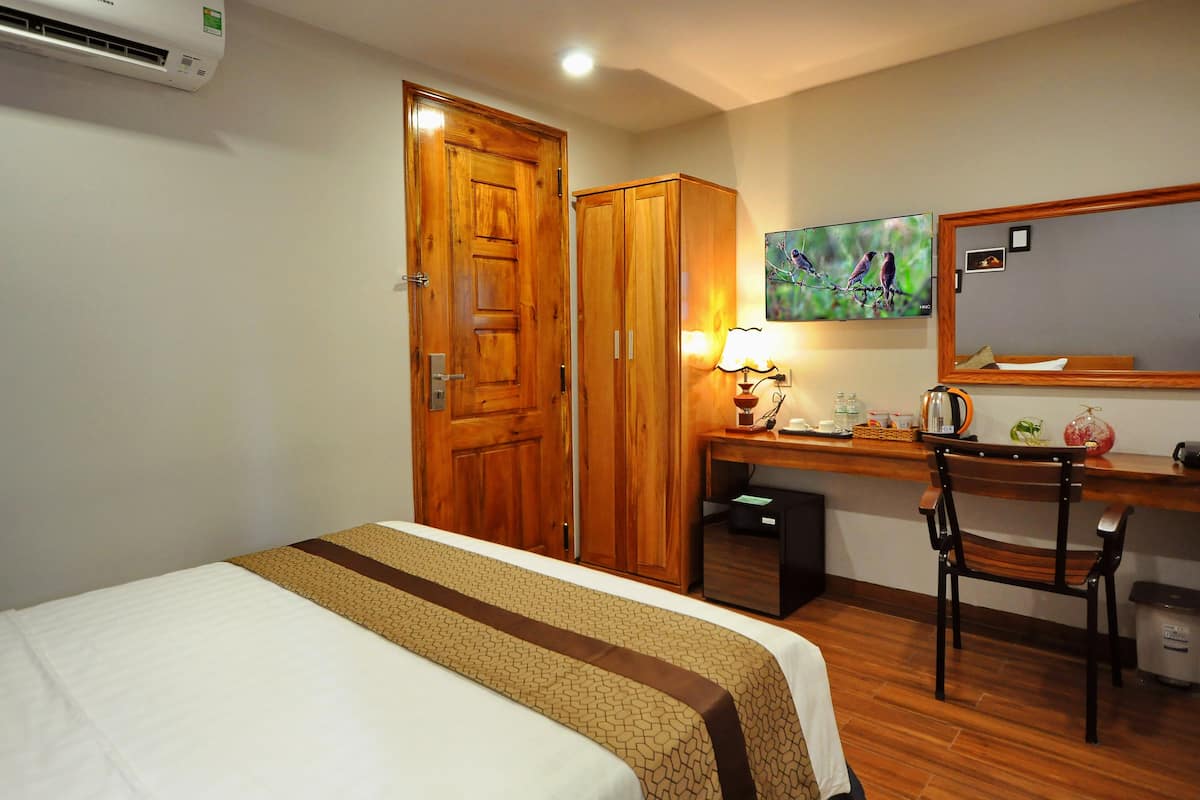 Une chambre d’hôtel équipée d’un lit, d’un bureau, d’une chaise, d’une armoire et d’un climatiseur fixé au mur.