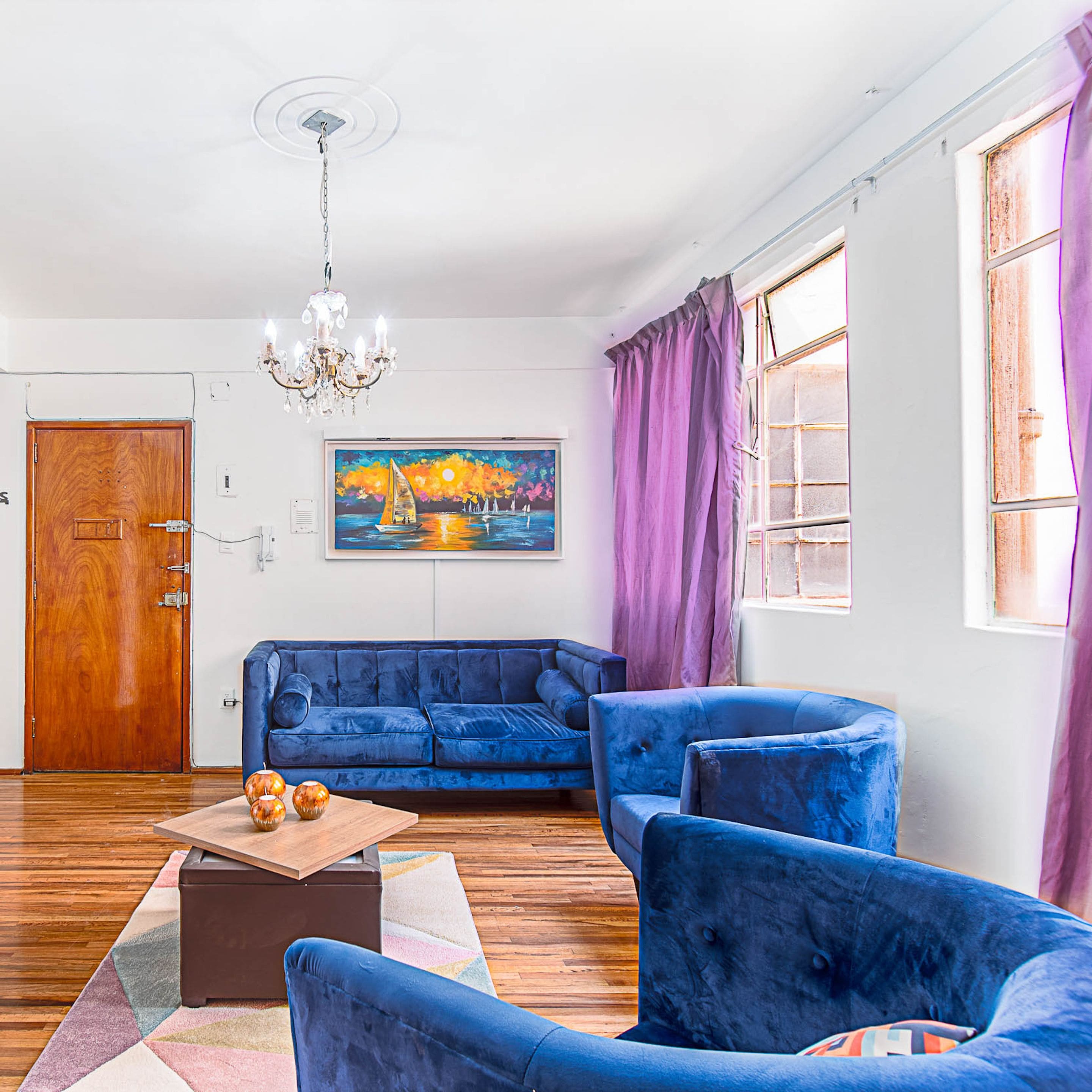A living room with a blue sofa, a wooden coffee table, and a painting of a sailboat on the wall.