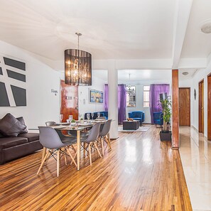 A modern living room with a dining area, wooden flooring, and contemporary furniture. - Roma Sur Balcony Apartments - Family Friendly (Mexico City)