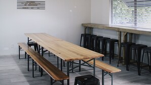 A modern dining area with a long wooden table, black benches, and pendant lighting.