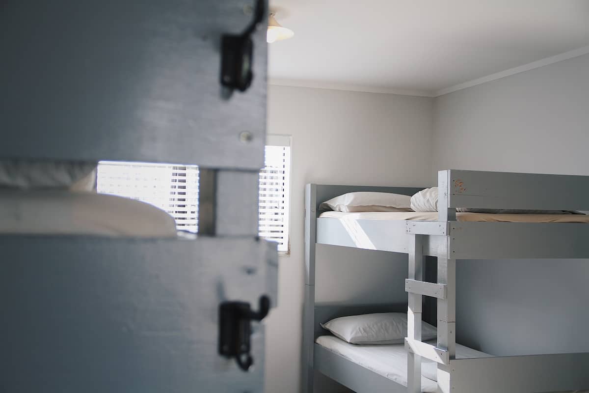 A bunk bed room with a window, a door, and a light fixture.
