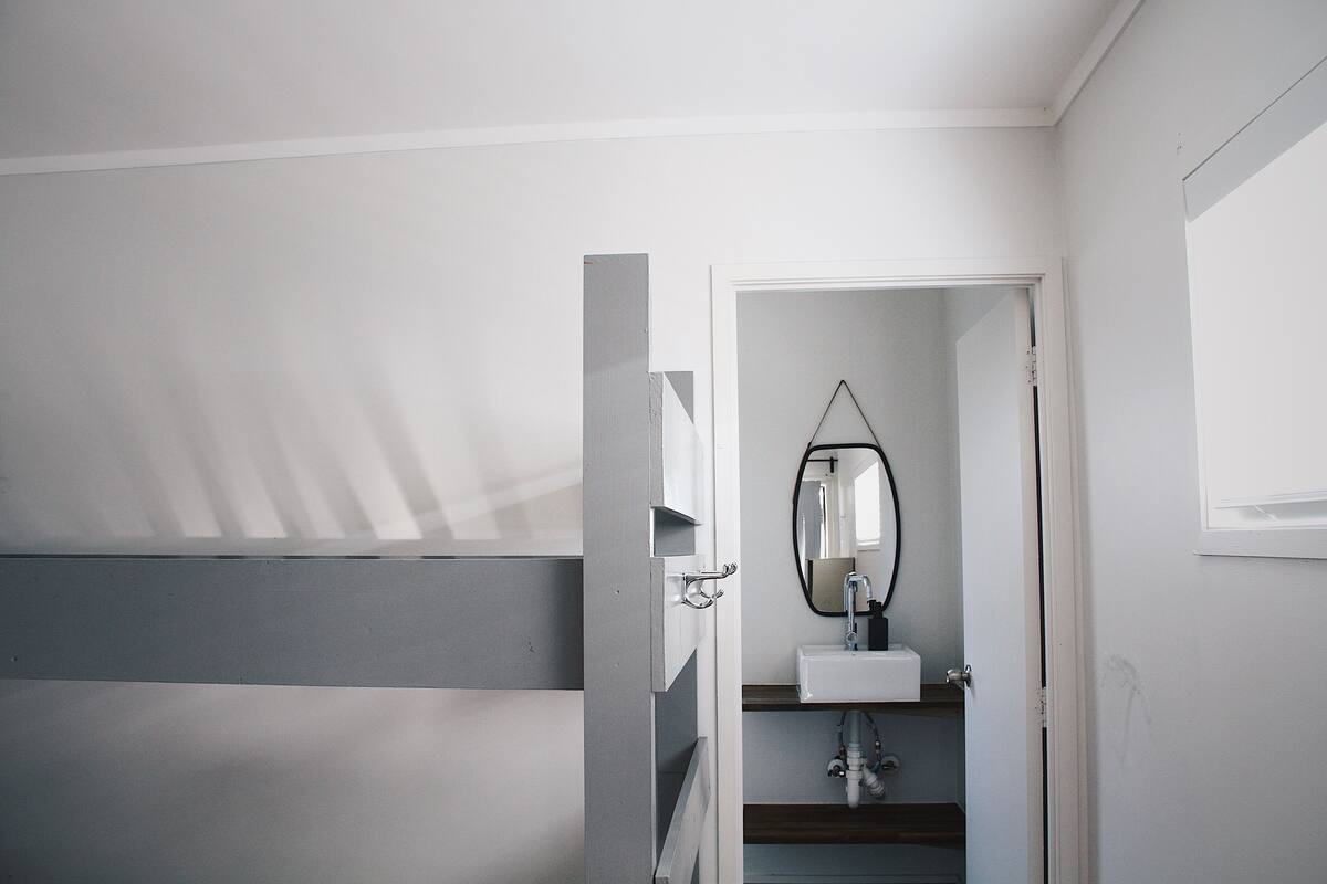 A bathroom with a white sink, a mirror, and a door leading to another room.