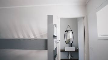 A bathroom with a white sink, a mirror, and a door leading to another room.