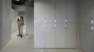 A modern hotel corridor with lockers numbered 923-928 and a person walking towards the lockers.