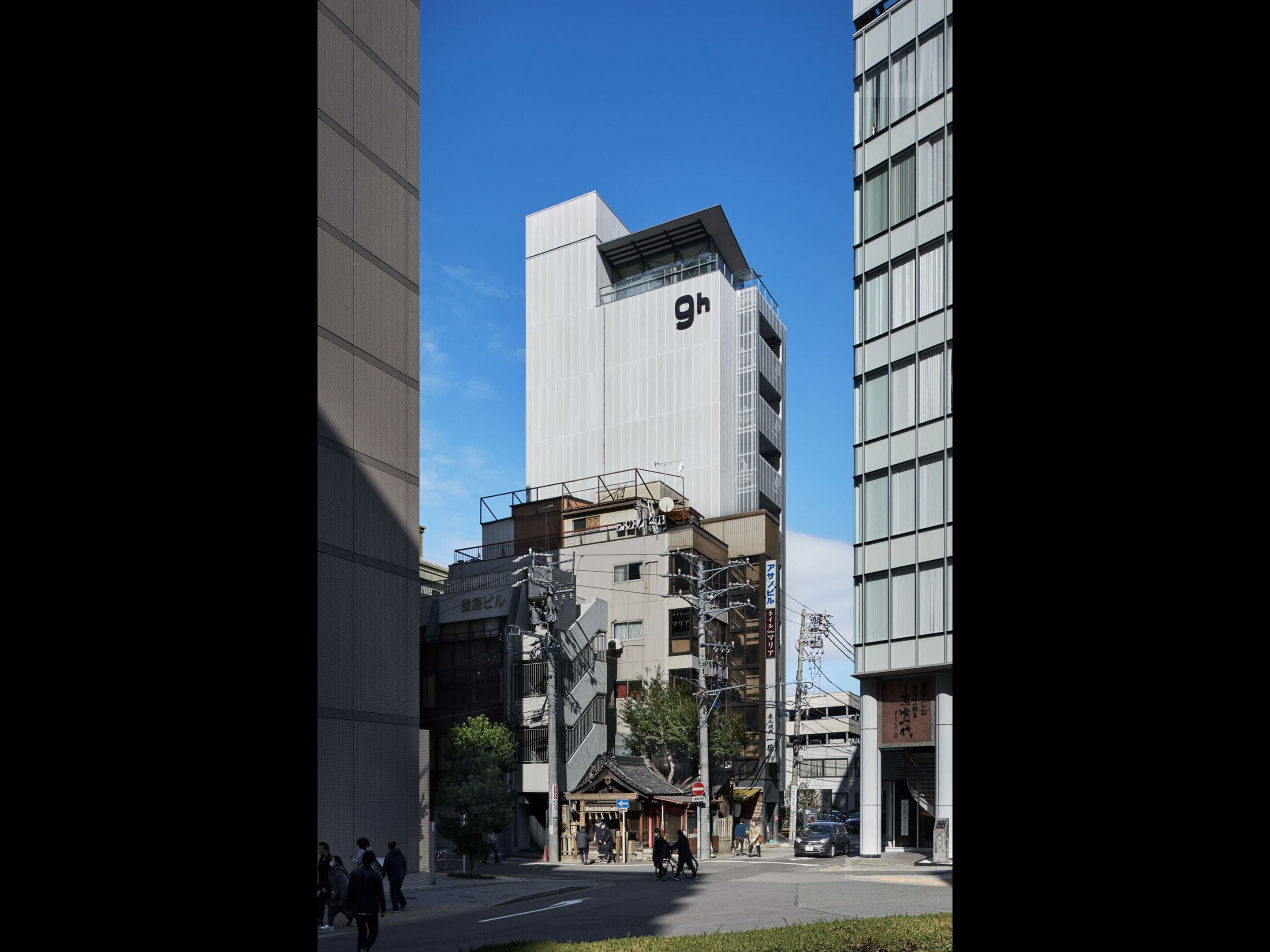 A modern urban street with tall buildings, a traditional wooden structure, and pedestrians.