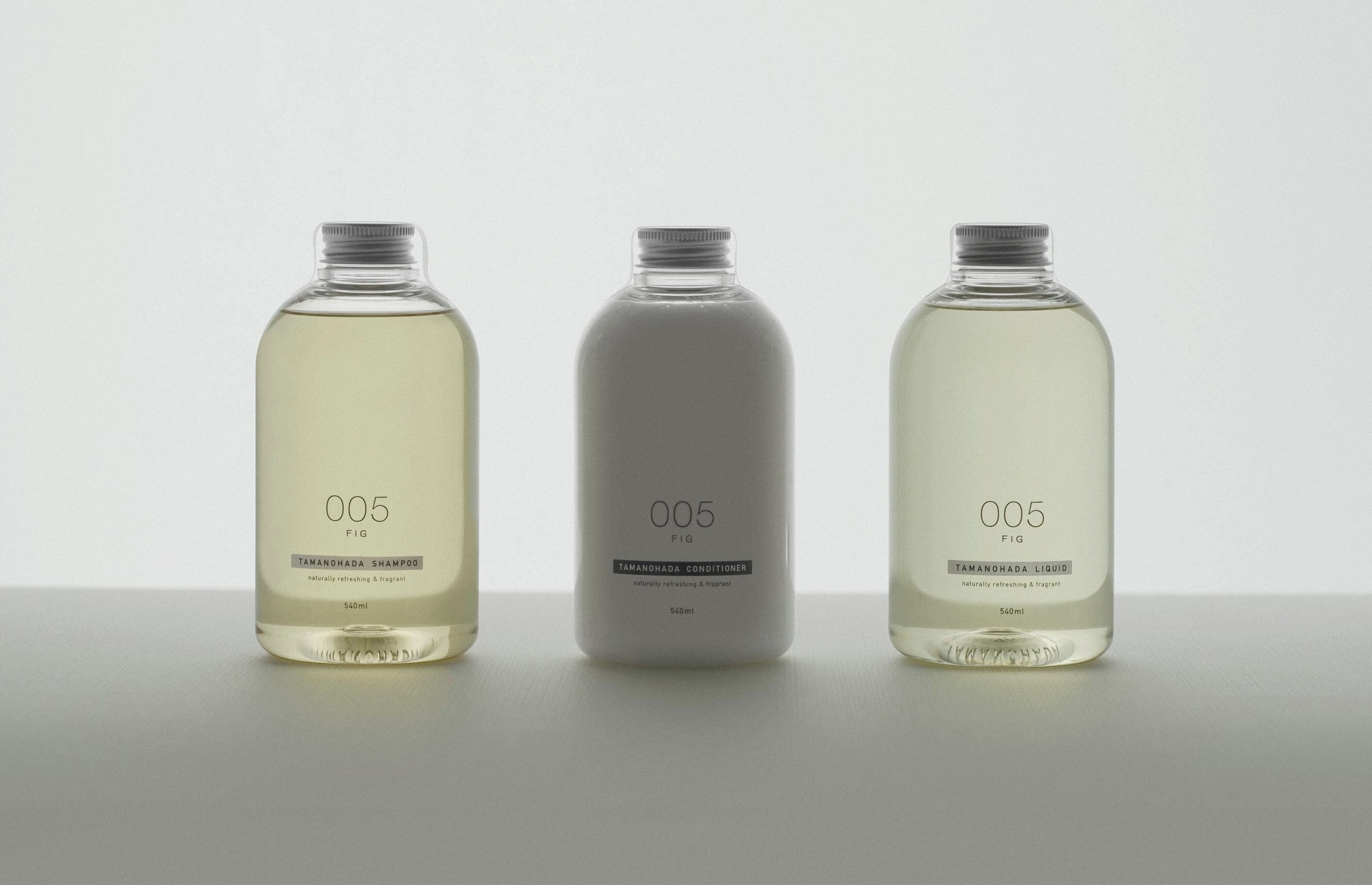 Tres botellas de un producto con la etiqueta '005 FIG' que contienen diferentes tipos de líquido.