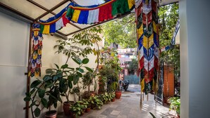A narrow courtyard with potted plants and colorful prayer flags. - Hotel Yambu (Kathmandu)