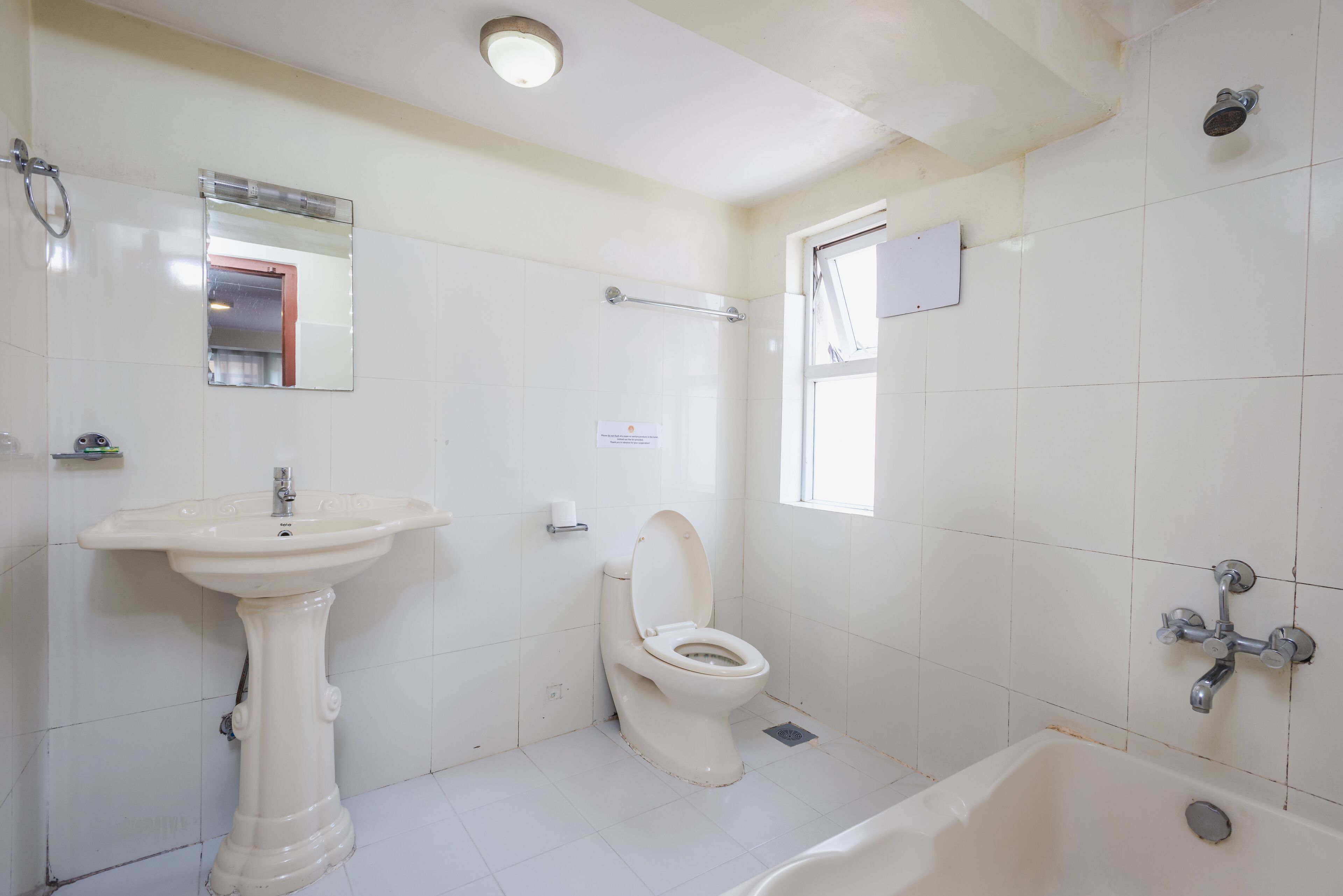 A bathroom with a pedestal sink, toilet, bathtub, and a window.
