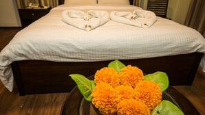 A hotel room with a large bed, a bedside table with a phone, and a floral arrangement on the floor. - Hotel Yambu (Kathmandu)
