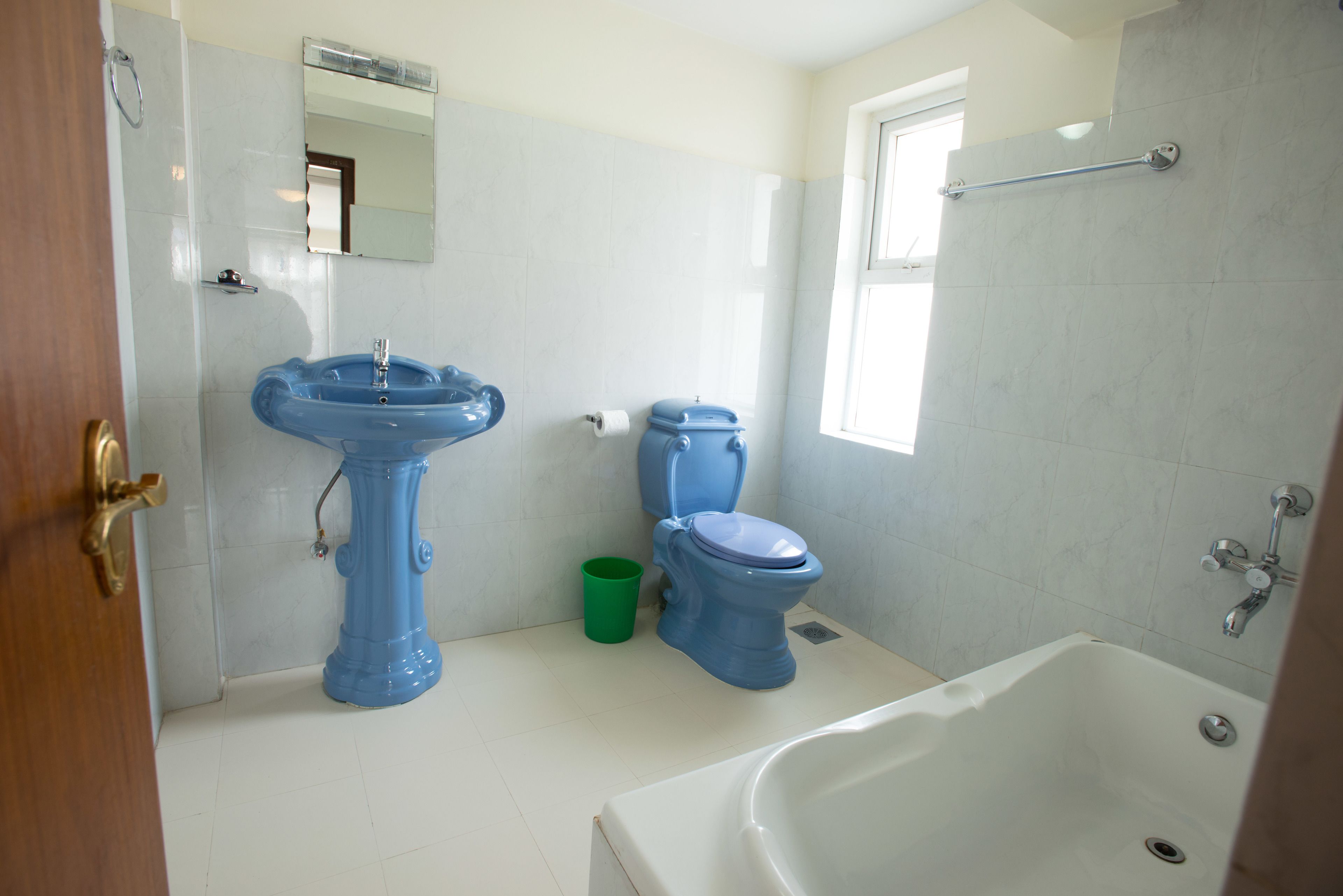 A bathroom with a white bathtub, a blue sink, and a toilet.