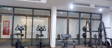 A gym with cardio machines, weightlifting equipment, and a bench.