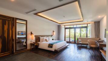 A modern hotel room with a large bed, a sofa, a desk, and a dining table.