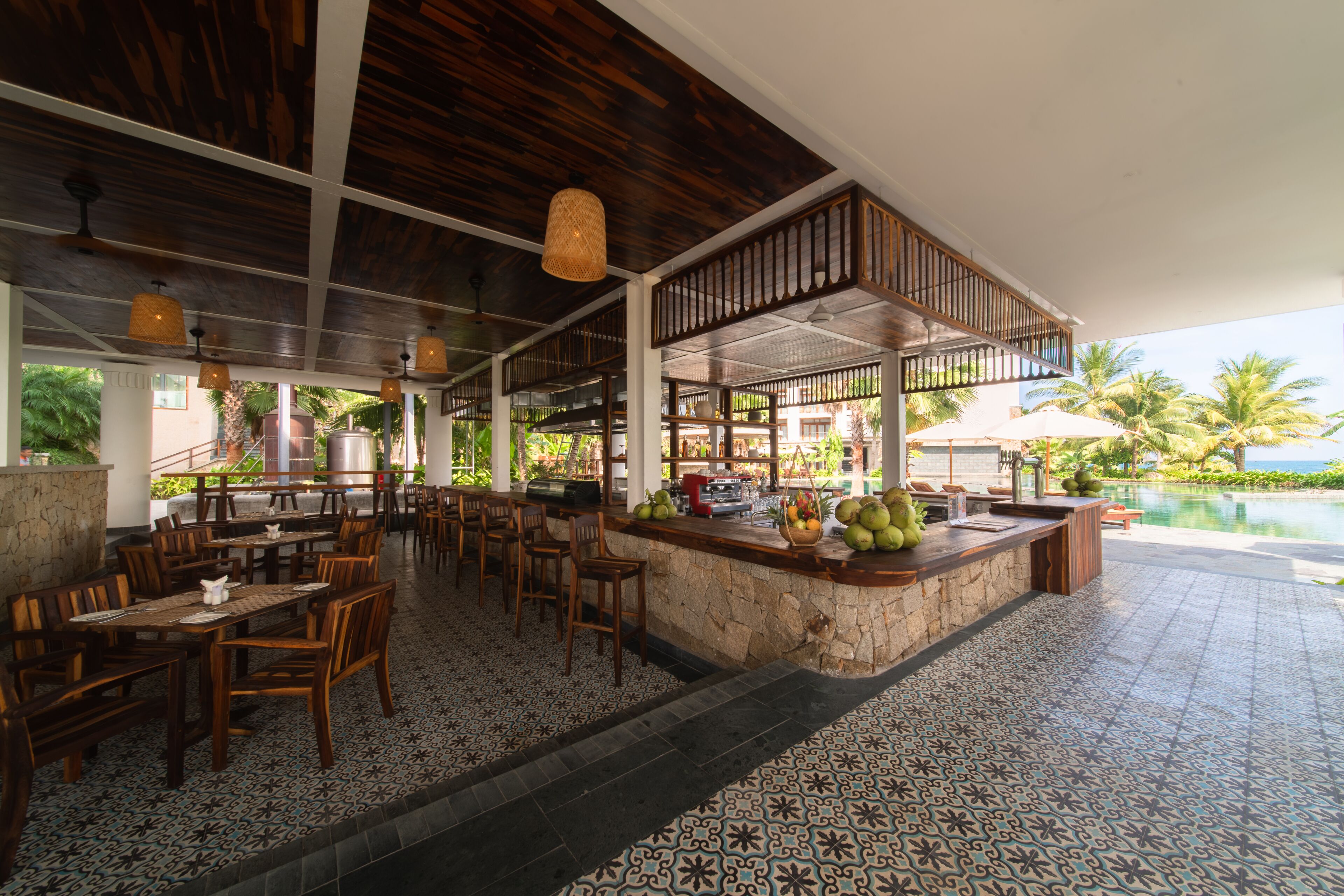 A restaurant with wooden furniture, a stone bar, and a view of the ocean.
