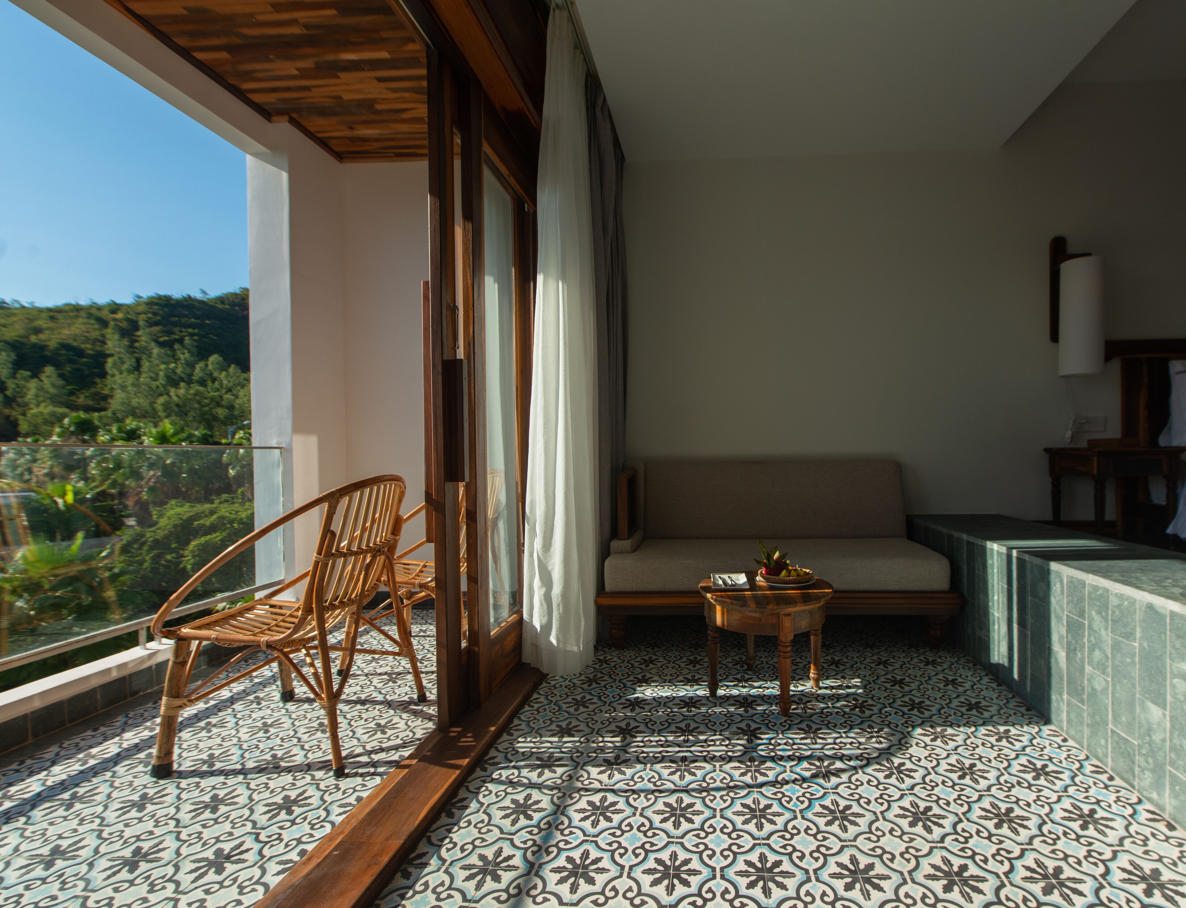 Un balcon avec un fauteuil en osier, un canapé et une petite table.