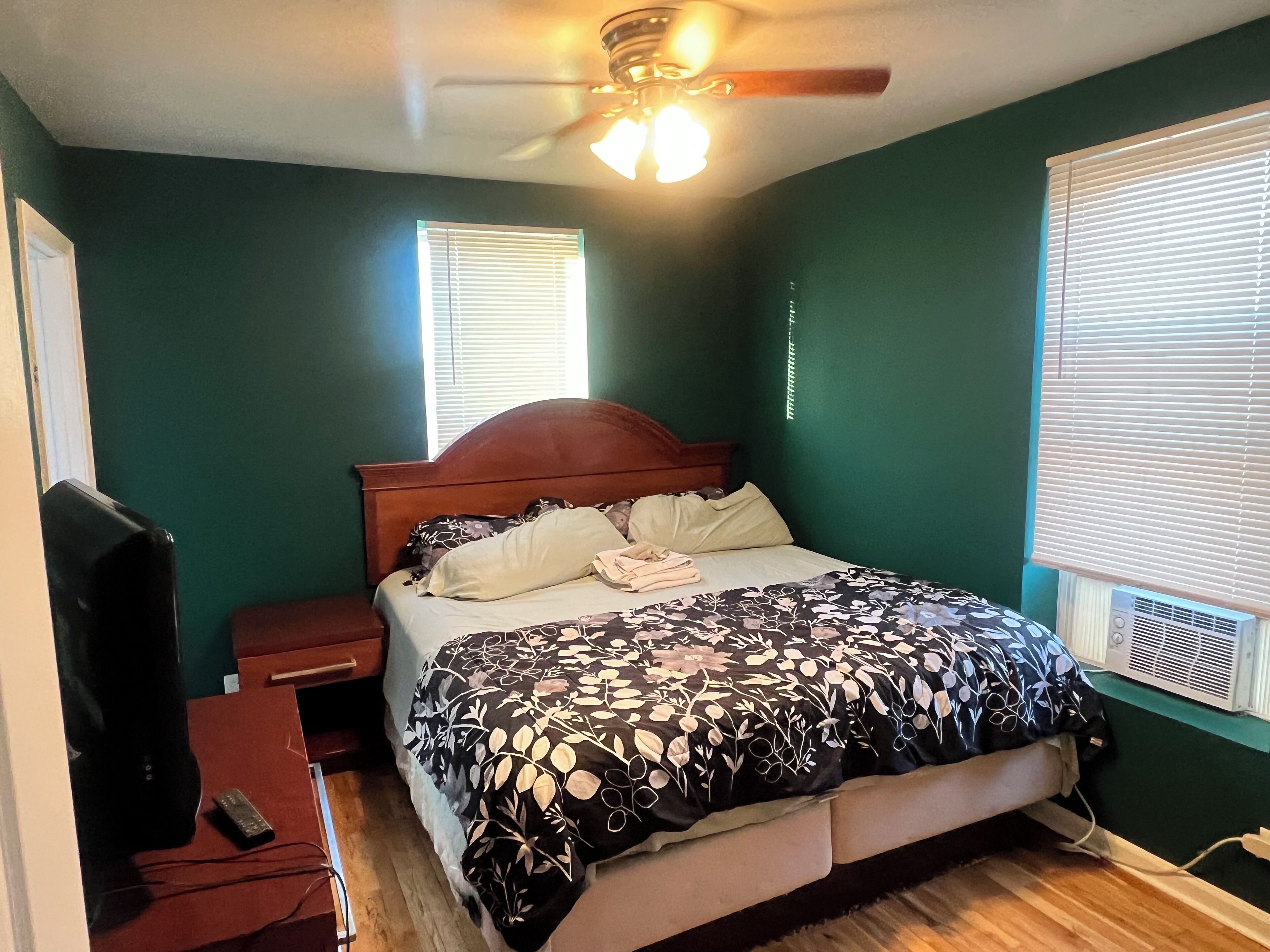 Une chambre à coucher avec un lit, une table de chevet et un ventilateur de plafond.