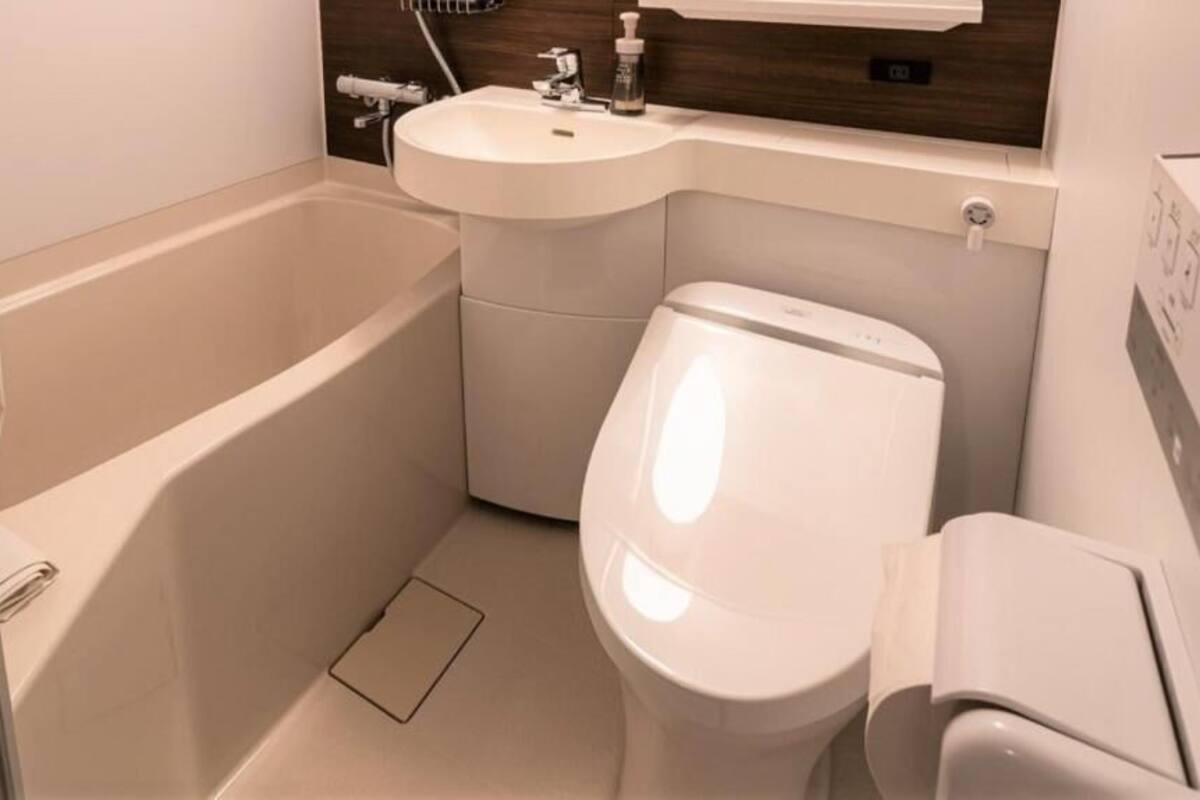 A bathroom with a bathtub, toilet, sink, and a showerhead.