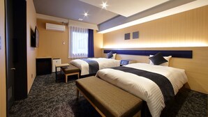 Una camera d'albergo con due letti, una scrivania, una sedia e un tavolino.