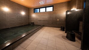 Una moderna sala spa con una grande vasca idromassaggio, soffitto in legno e pareti piastrellate.
