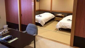 A hotel room with two beds, a desk with a chair, and a small table with a remote control. - Hotel Arima Koukaen (Nishinomiya)