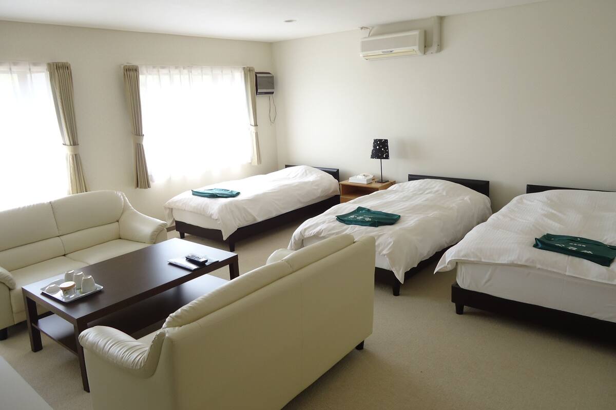 Een hotelkamer met twee bedden, een bank, een bijzettafeltje en een lamp.